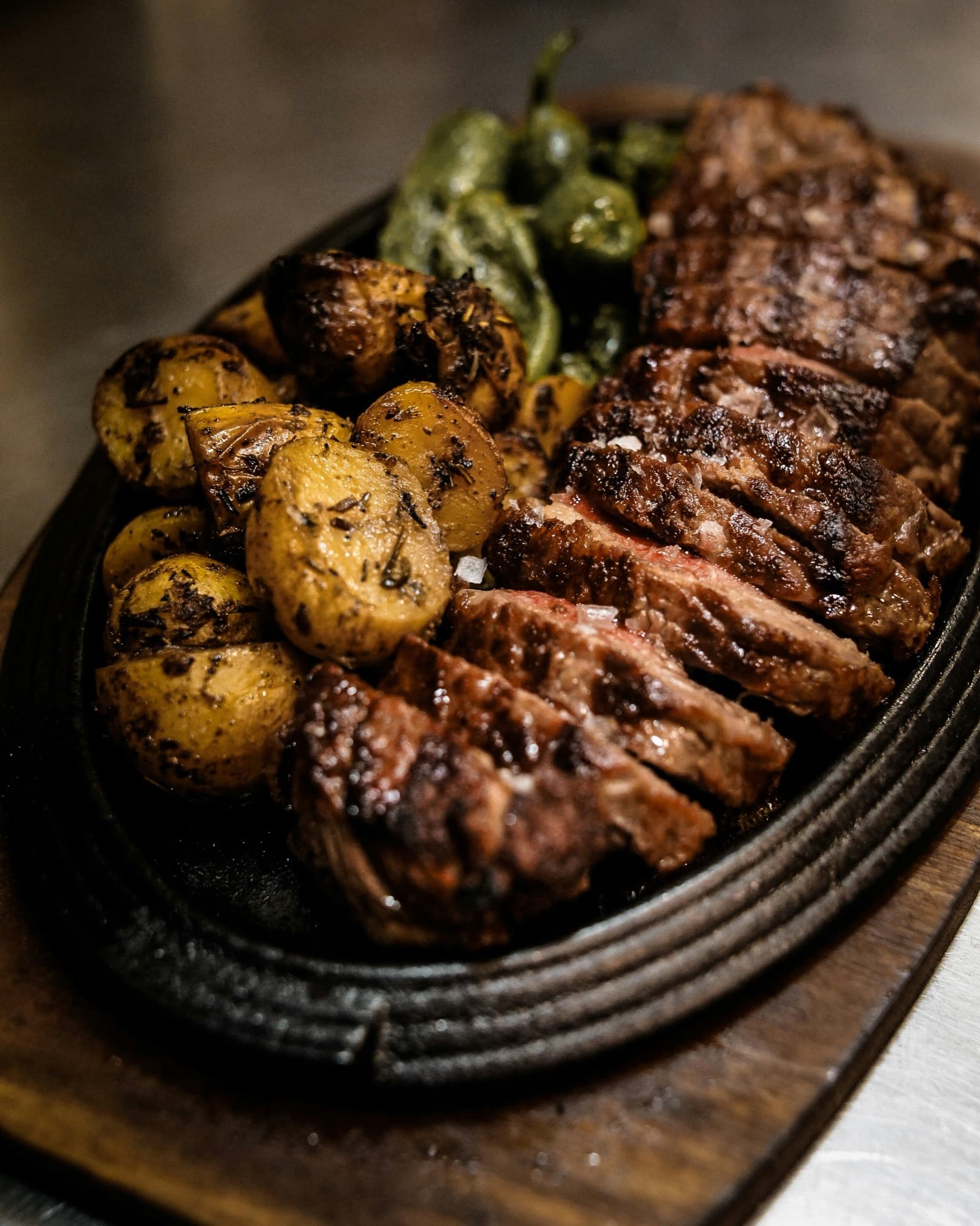 A traditional Argentine asado of grilled beef and potatoes served on cast iron